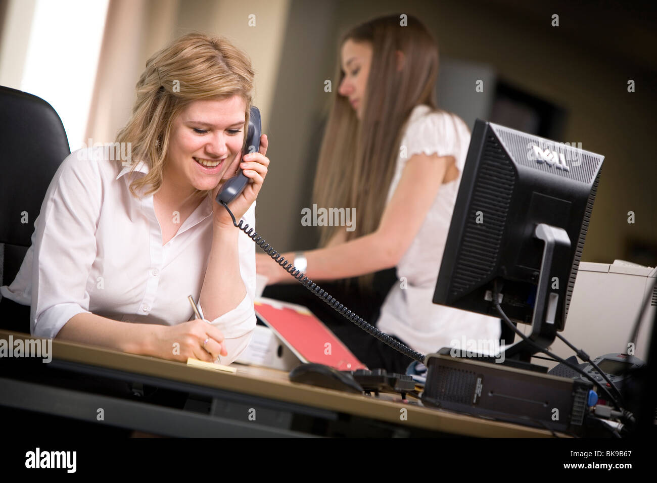 Felice segretario fa una telefonata in ufficio. Foto Stock