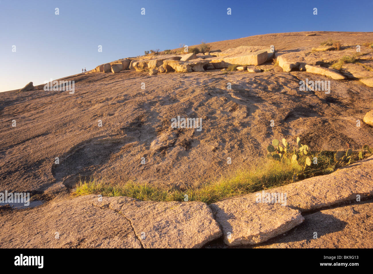 Massi di granito e sfogliato strati di granito, gli escursionisti a lunga distanza al tramonto vicino al vertice della roccia incantata, Texas, Stati Uniti d'America Foto Stock