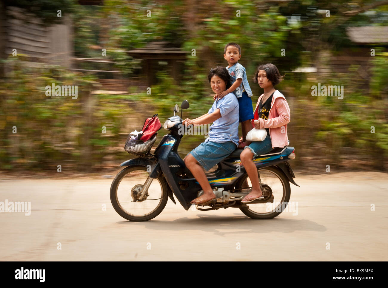 Famiglia equitazione motocicletta attraverso il villaggio lungo il Mae Taeng fiume nelle zone rurali a Chiang Mai Provincia, Thailandia. Foto Stock