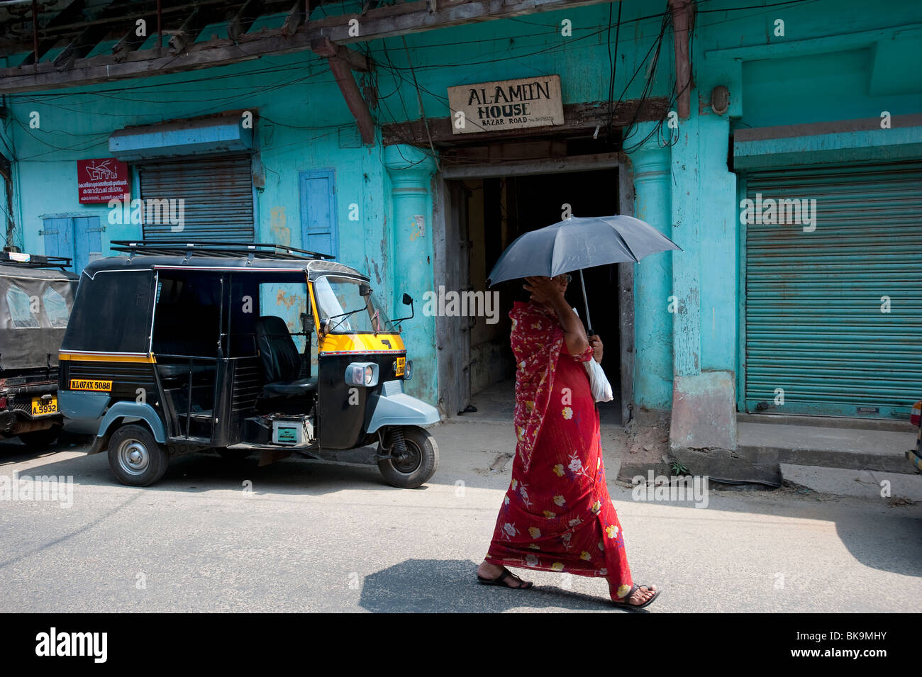 Donna locale a piedi passato negozio magazzino vicino al lungomare, Fort Cochin, Kerala, India Foto Stock