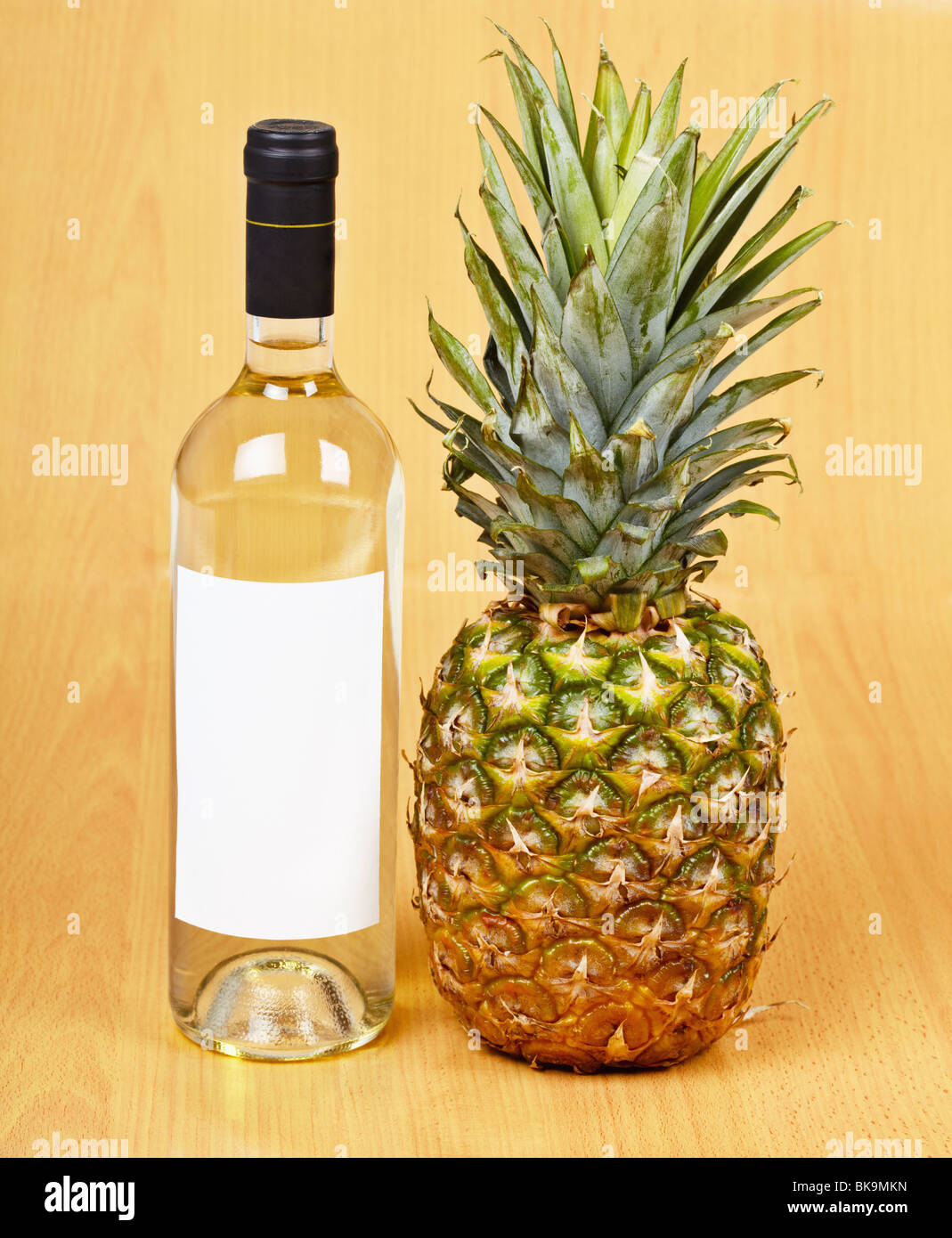 Una bottiglia di vino bianco e un grande ananas maturo Foto Stock