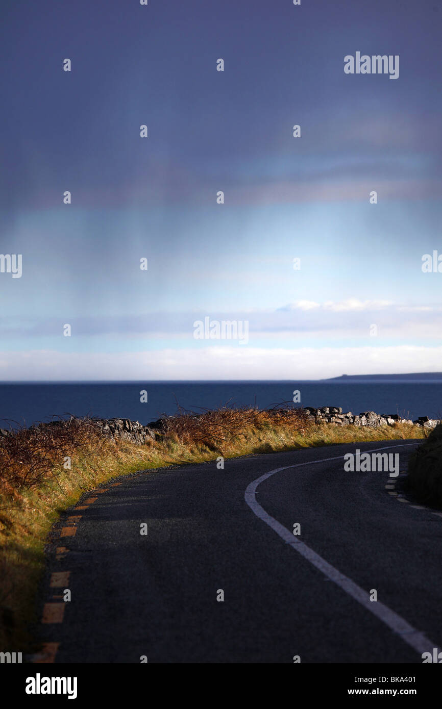 La mattina presto la luce del sole illumina la strada in The Burren, Co. Chiara sulla costa occidentale dell' Irlanda Foto Stock