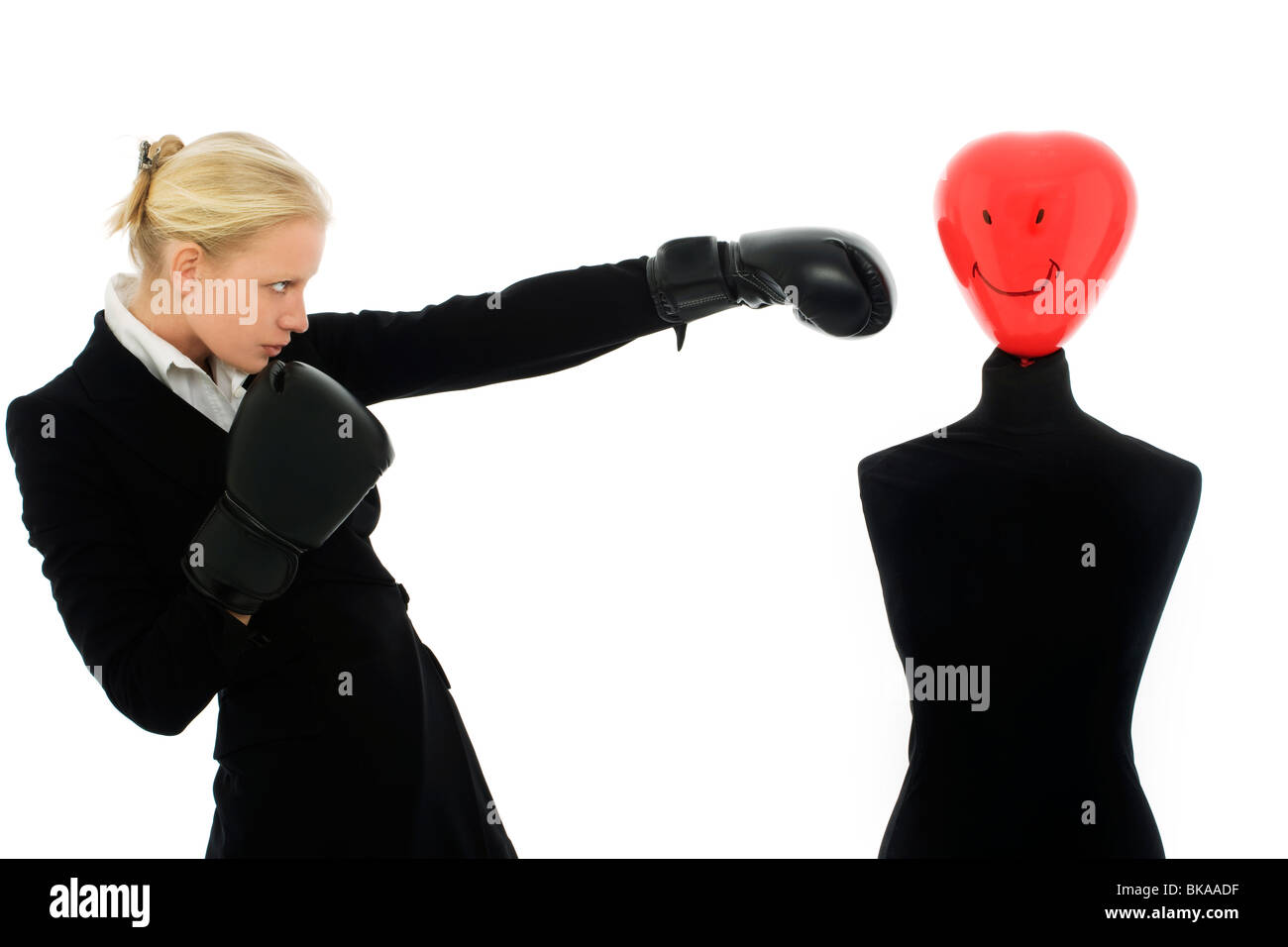 Ritratto di una giovane imprenditrice caucasici con aria aggressiva indossa guantoni da pugilato e punzoni un dummy Foto Stock