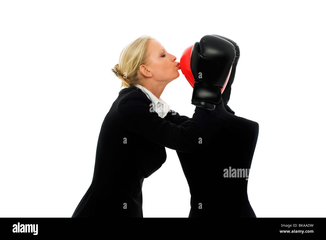 Ritratto di una giovane imprenditrice caucasici con aria aggressiva indossa guantoni da pugilato e baciando un dummy Foto Stock