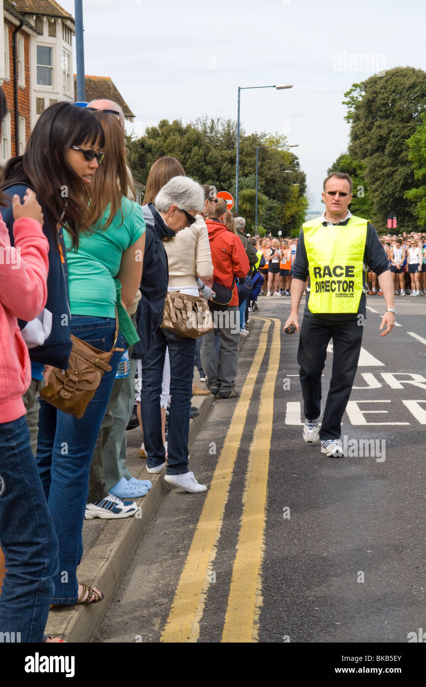 Attesa di persone su strada all'inizio di una gara. Il direttore di gara assicura che non vi sia nessuno nel modo. Foto Stock