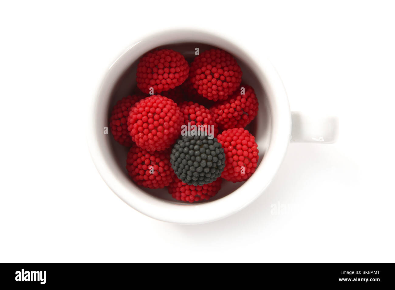 La caramella di ribes rosso e uno nero diverso in un bianco tazza di caffè Foto Stock