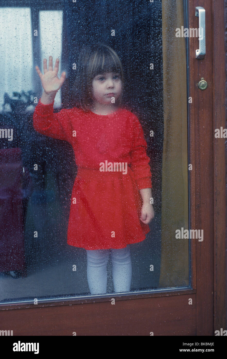 Moody shot della bambina in attesa presso la finestra Foto Stock