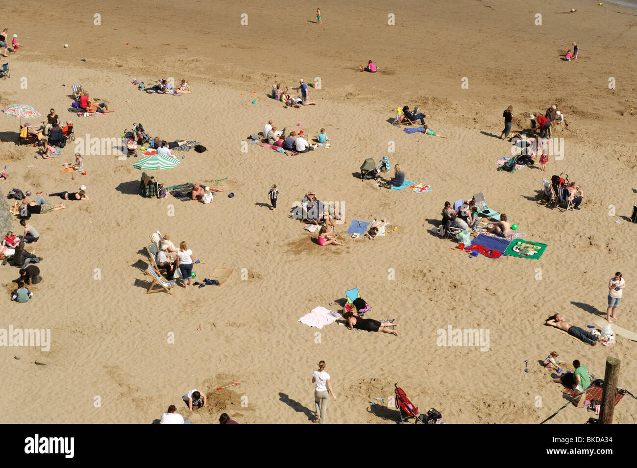 Persone, famiglie, a prendere il sole sulla spiaggia di sabbia a New Quay, Ceredigion, Wales UK Foto Stock