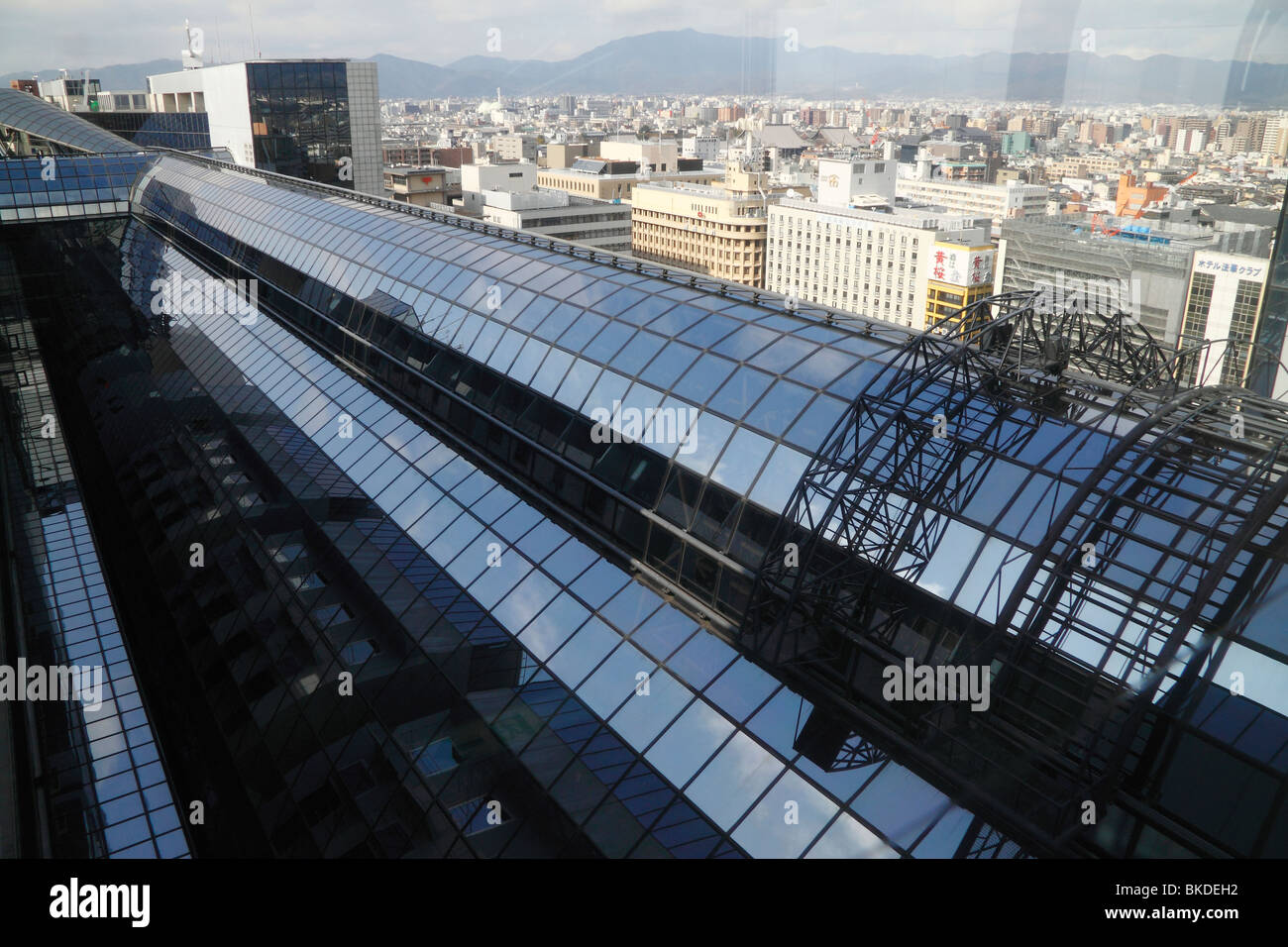 Una forma circolare arcuato a soffitto di vetro della hall centrale di Kyoto stazione ferroviaria con cielo blu riflessioni e dello skyline della città Foto Stock