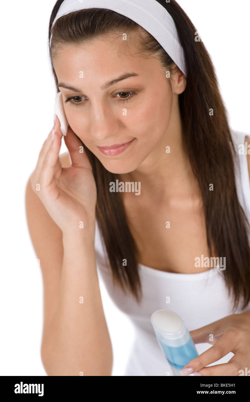 Bellezza viso - Teenager donna acne per la pulizia della pelle con il tampone di cotone su sfondo bianco Foto Stock