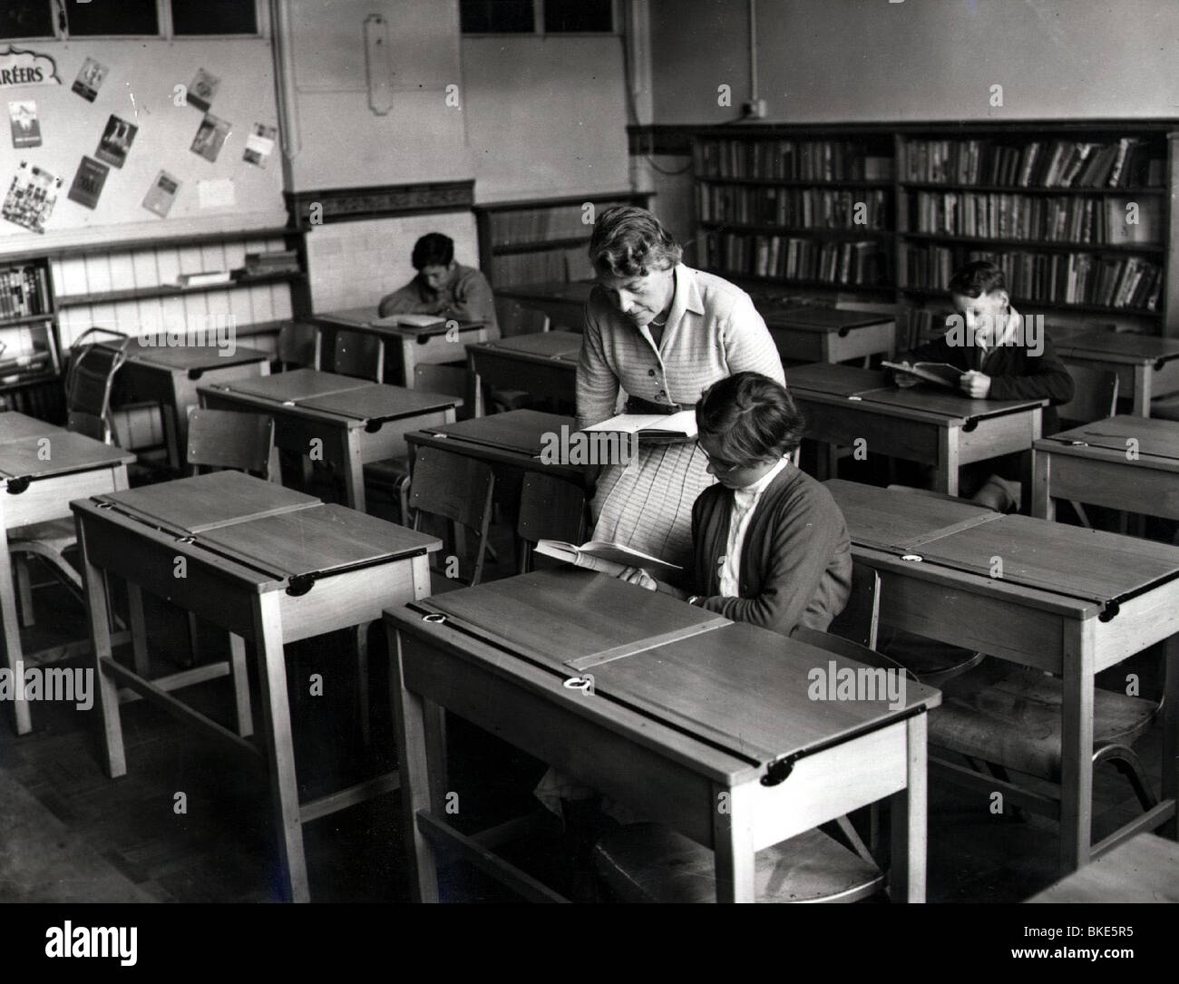 Studenti, insegnanti che leggono con pochi alunni in un libro, durante una pandemia asiatica di influenza 1957, Foto Stock