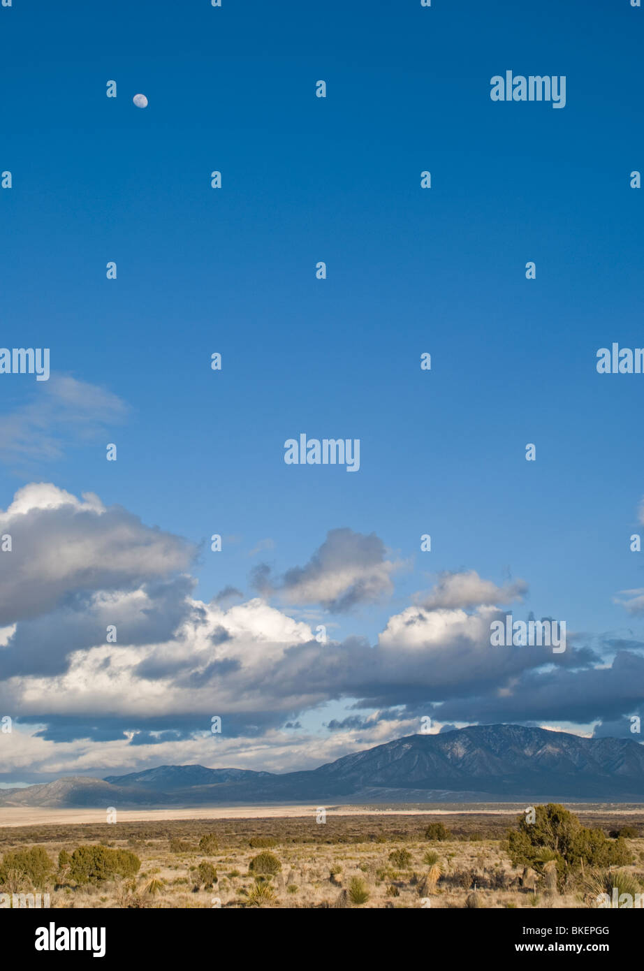 Nuvole scure passare il puntatore del mouse vicino al Carrizo Mountians, mentre quasi una luna piena galleggianti nel cristallo azzurro del cielo sopra. Foto Stock