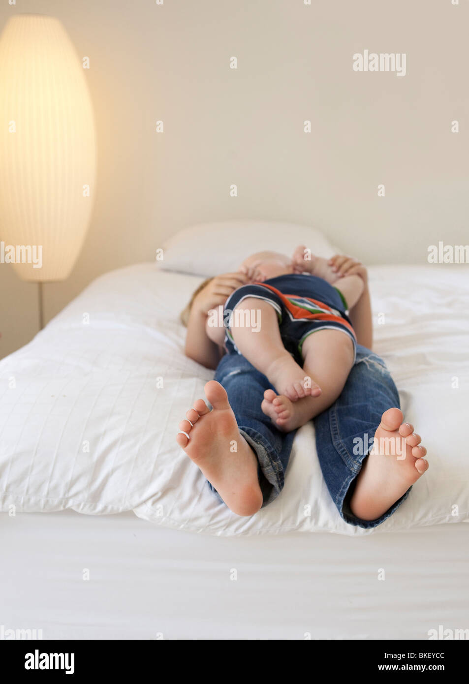 Piedi di giovani bambini hanging off il letto Foto Stock