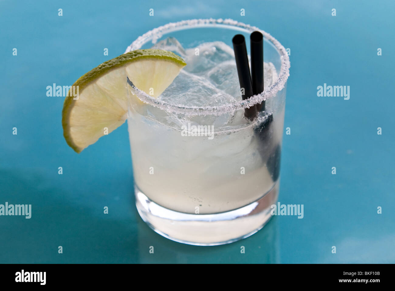 Perfetto Margarita classico con uno spicchio di lime e il ghiaccio è servita in chiaro lo sbarramento rotante sul tavolo blu top presso un bar sul tetto in Città del Messico MESSICO Foto Stock