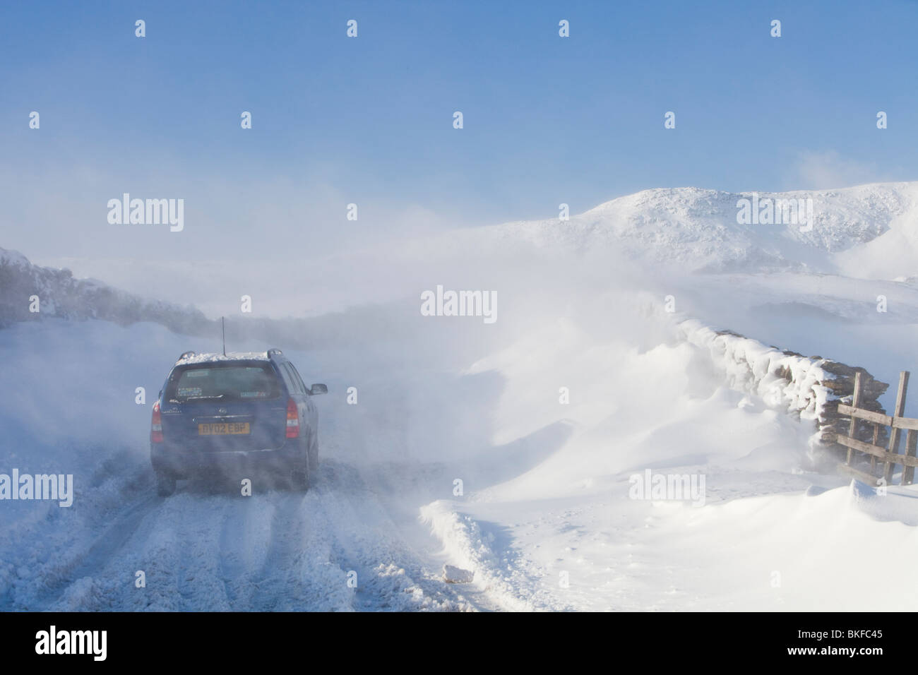 Un auto è abbandonato sul Kirkstone pass road sopra Windermere dopo che è stato bloccato dalla spindrift vento e neve soffiata, UK. Foto Stock