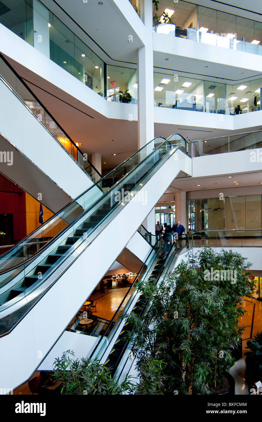 Interno di un eco friendly corporate business multinazionale edificio per uffici con più piani collegati con scale mobili. Foto Stock