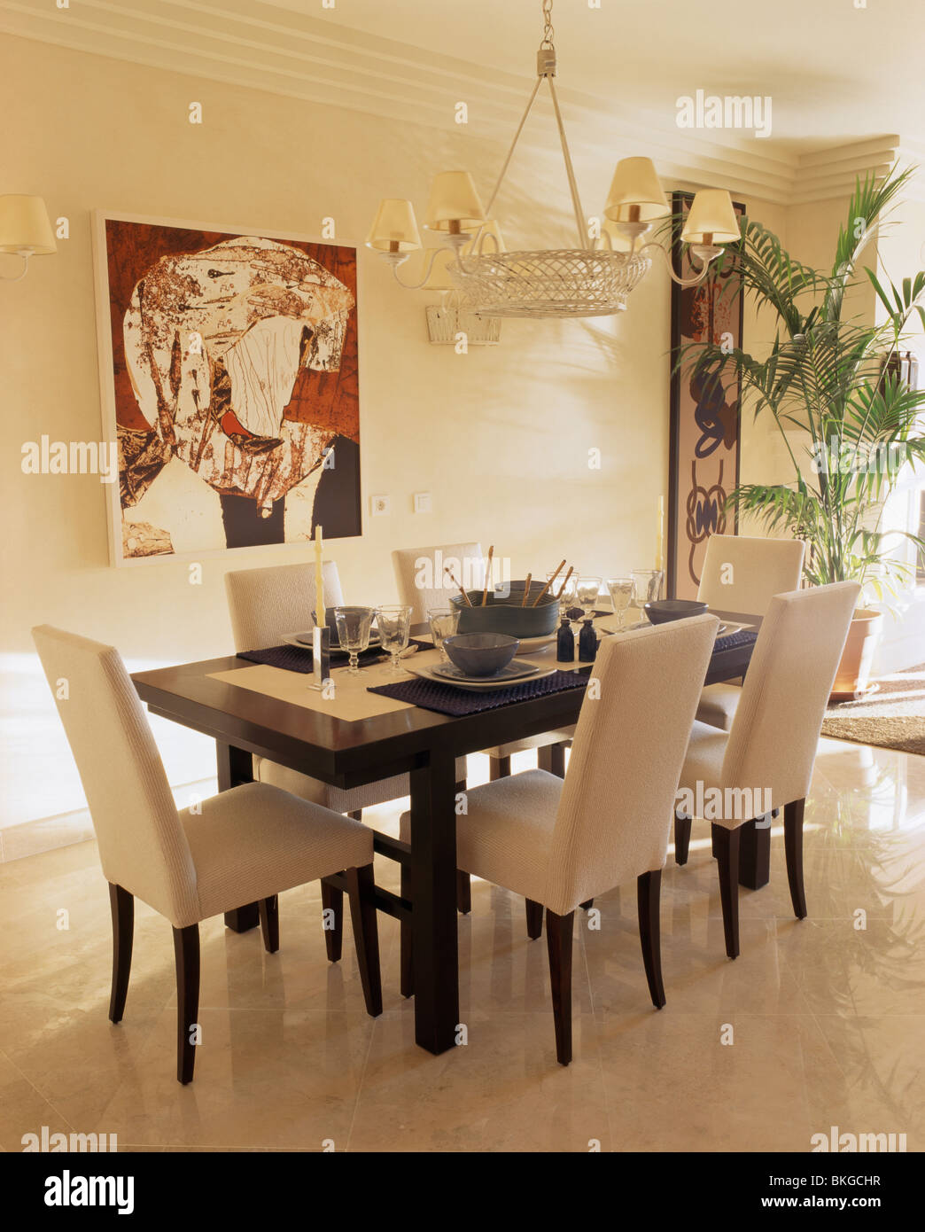 Tall-back crema sedie imbottite e tavola nera in bianca e moderna sala da pranzo con abstract foto sulla parete Foto Stock