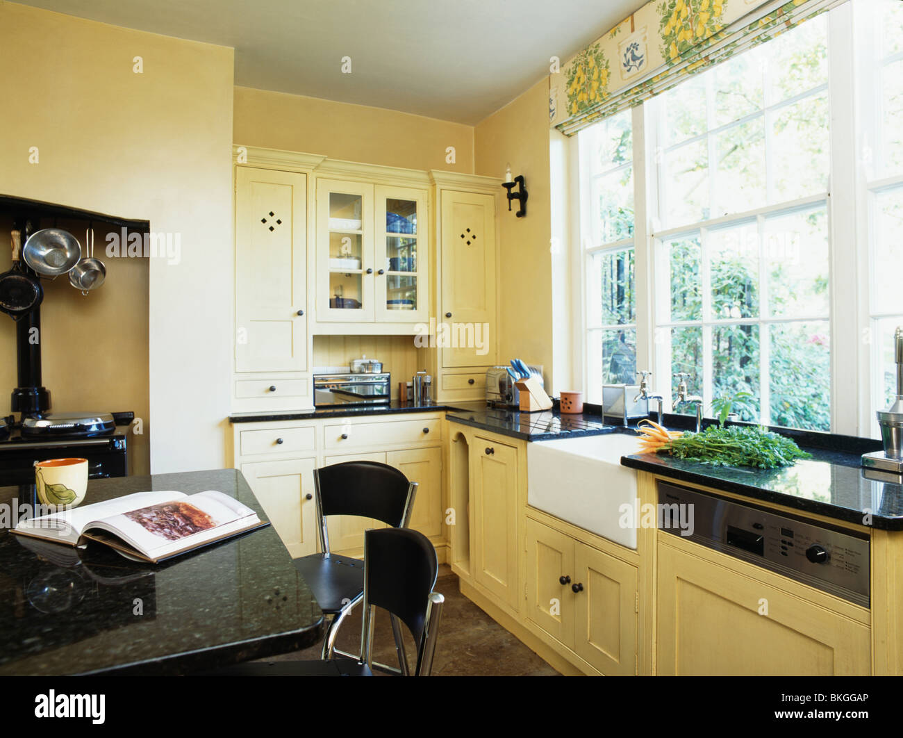 Nero con ripiano in granito unità isola in crema di moderna cucina dipinta in Farrow+vernice a sfera Foto Stock