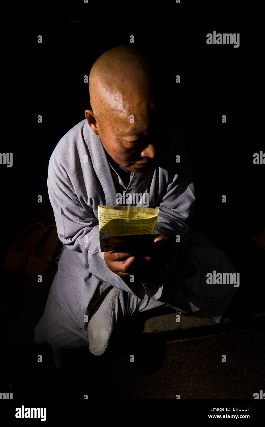Un monaco buddista di lettura del testo sacro nel bellissimo tempio Kaiyuan in Chaozhou. Foto Stock