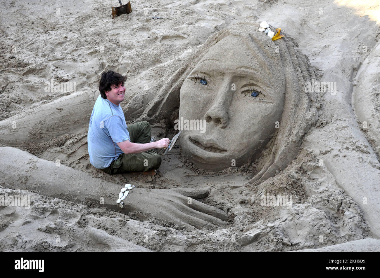 Un artista in sabbia a lavorare a bassa marea sul Tamigi London REGNO UNITO Foto Stock