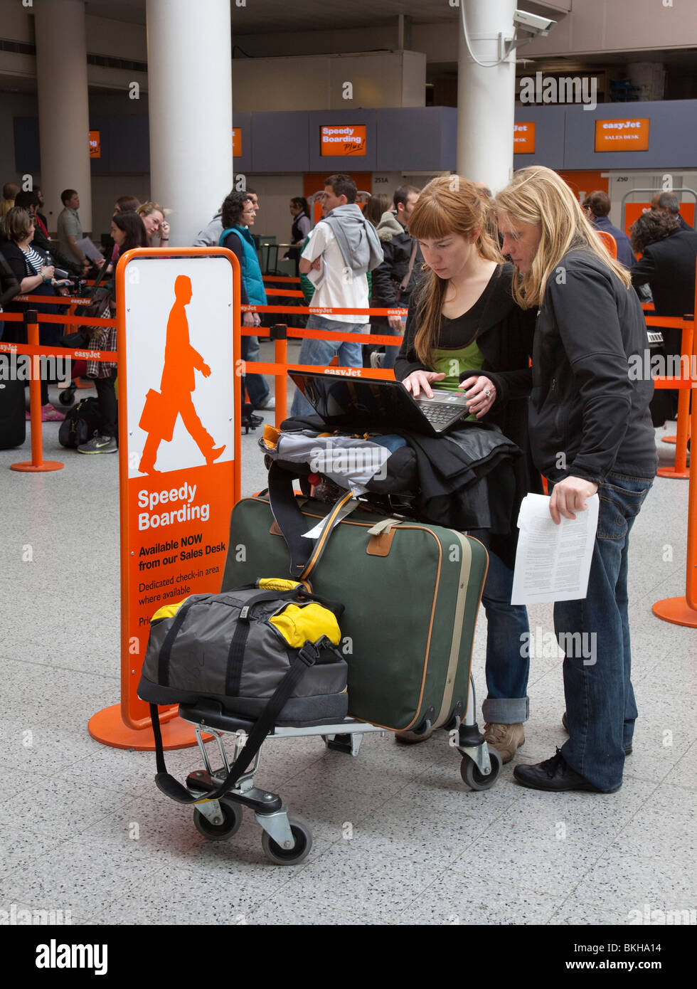 Giovane utilizzando il computer portatile per controllare i dettagli del volo in Atrio Partenze aeroporto di Gatwick Inghilterra REGNO UNITO Foto Stock
