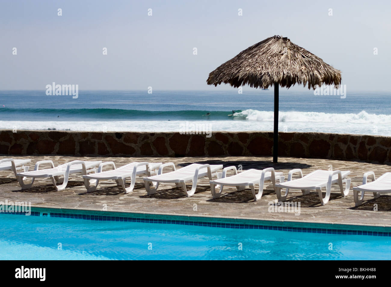 Un surfista cavalca un ondata di fronte a una piscina in stile resort nei pressi di Rosarito in Baja California. Foto Stock
