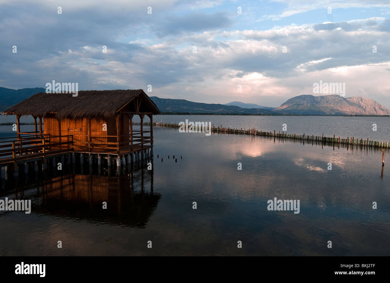 Legno casa di pescatori nel mezzo della laguna con acqua calma di messologhi al tramonto Foto Stock
