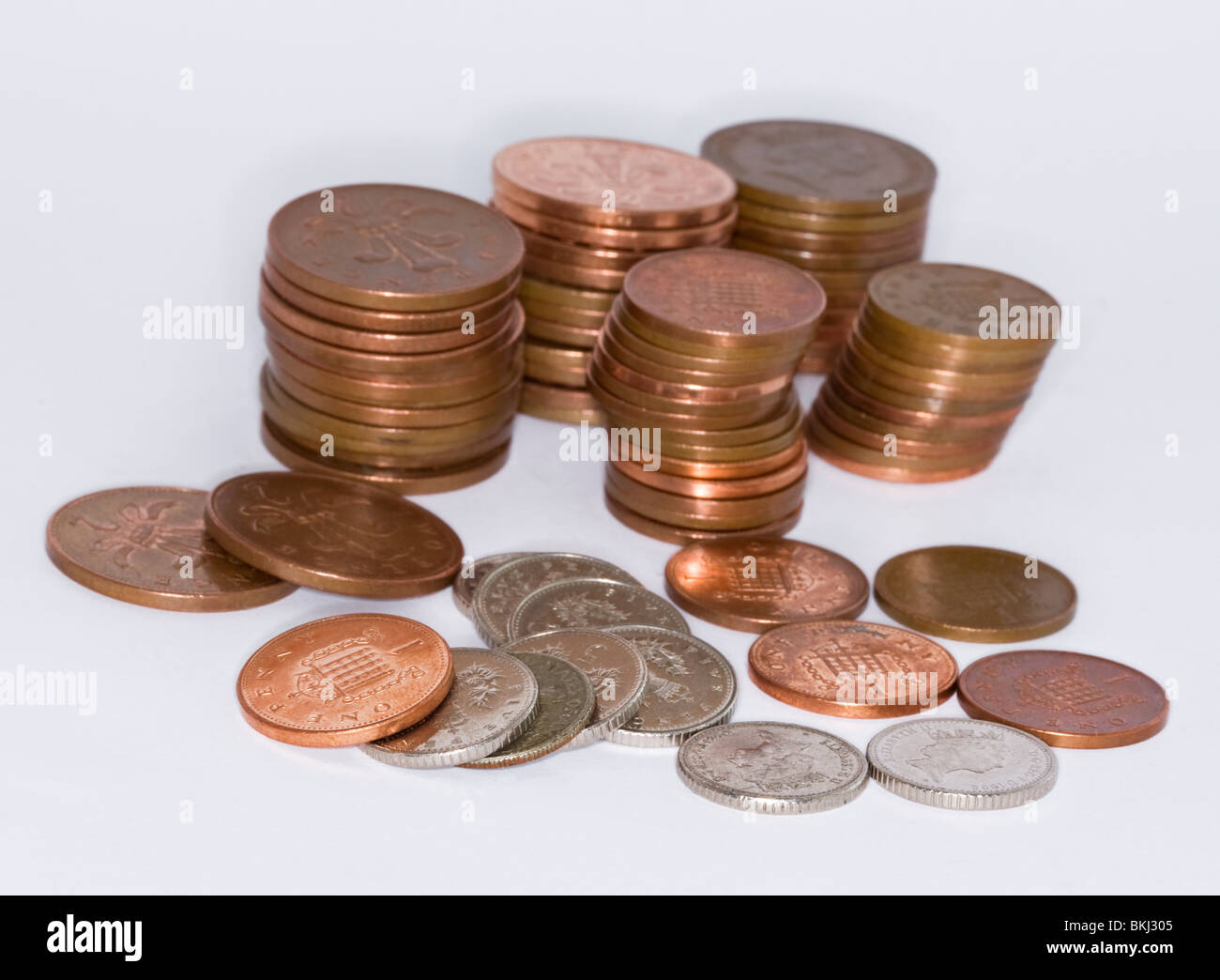 Pile di monete in inglese - due denari cinque pence e uno pence pezzi su sfondo bianco Foto Stock