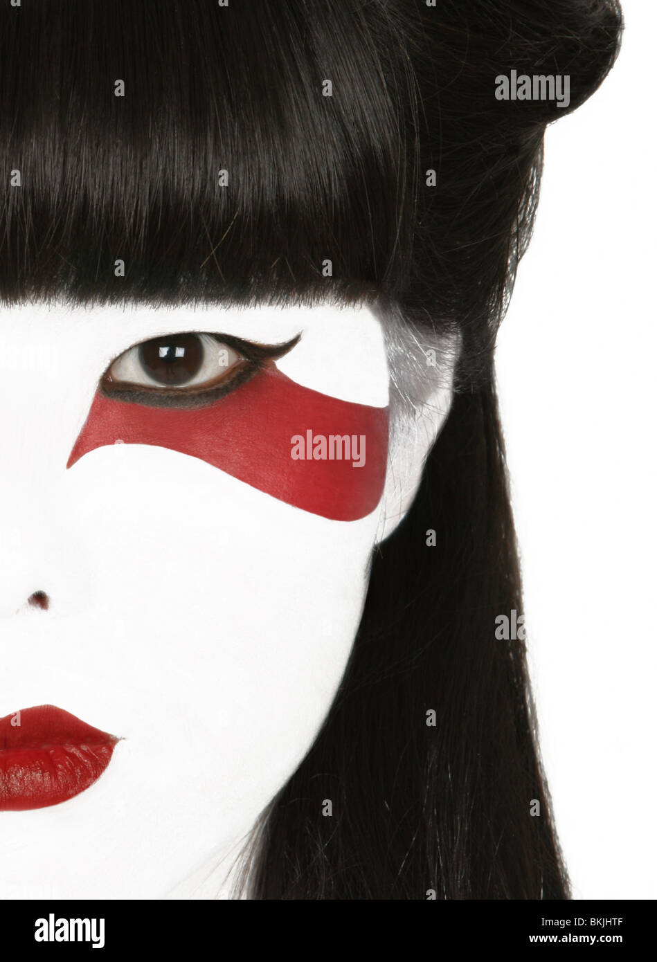 Una chiave di alta fotografia di un giapponese viso della bambina con la  geisha style make up e la stilizzazione di una striscia rossa sotto il suo  occhio sinistro Foto stock -
