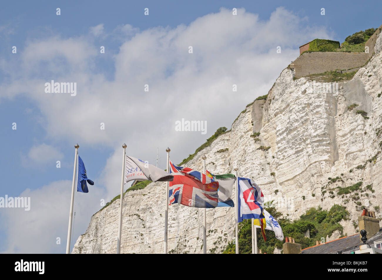 Le Bianche Scogliere di Dover con bandiere e Union Jack battenti in porto per traghetti Kent England Regno Unito Regno Unito Europa Foto Stock