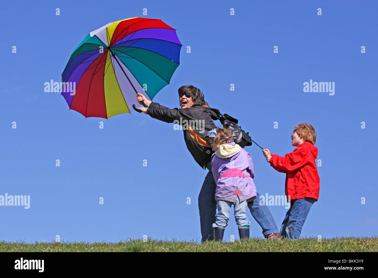 Bambini mantenendo la loro madre che viene soffiata via dal vento Foto Stock
