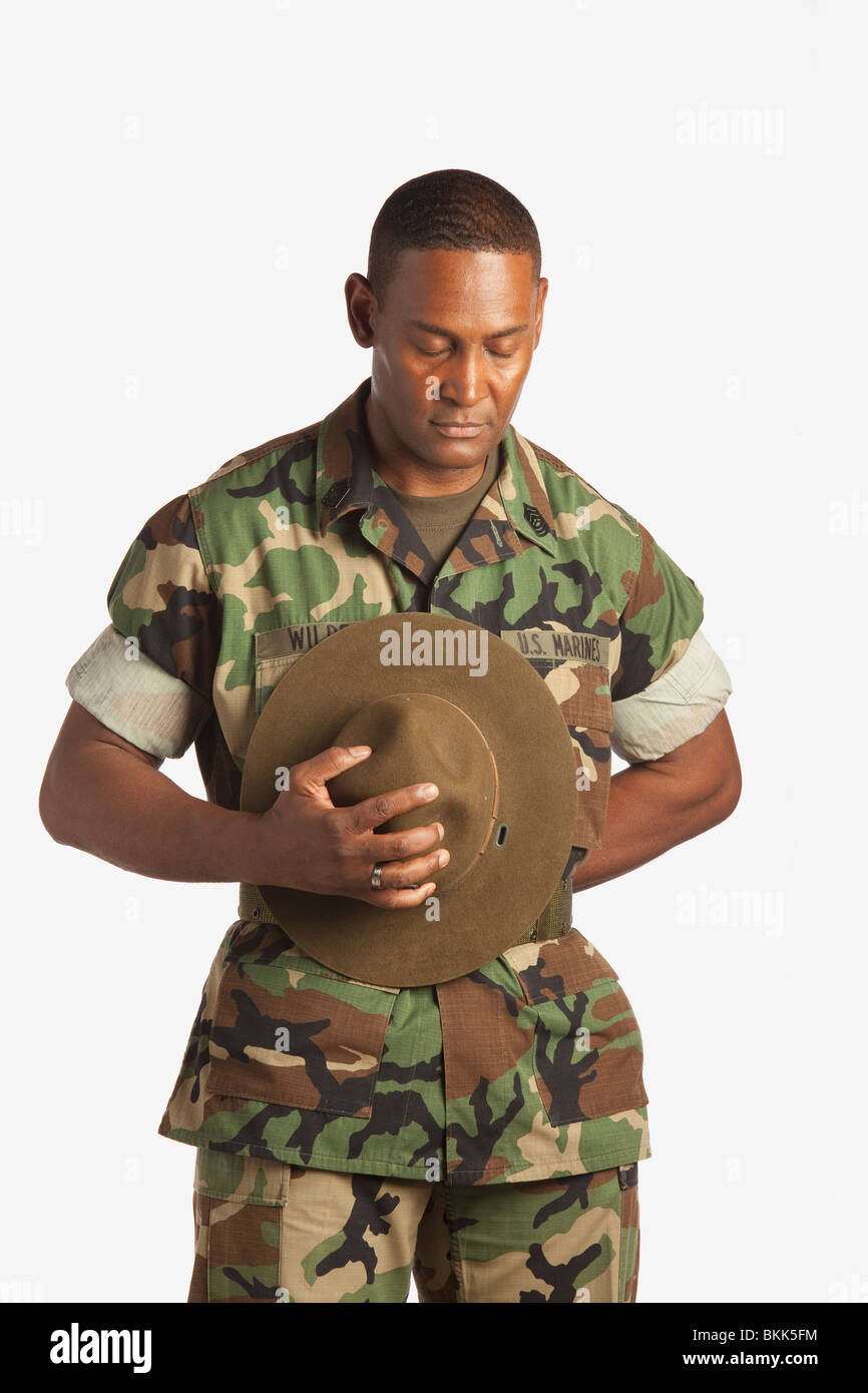 Un uomo militare tenendo il suo cappello con la sua testa piegata Foto Stock