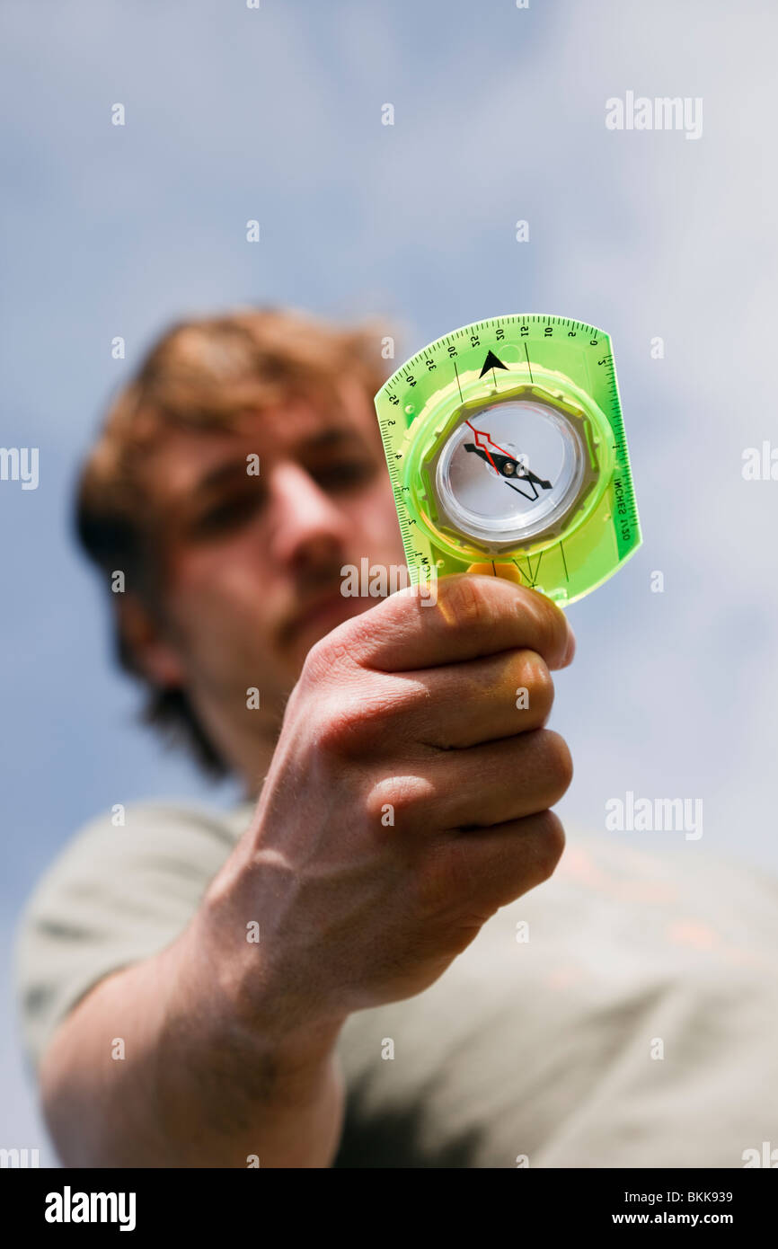 Giovane uomo millenario escursionista navigazione guardando e utilizzando la navigazione orienteering escursionismo compasso in mano al punto giusta direzione avanti. Regno Unito Gran Bretagna Foto Stock