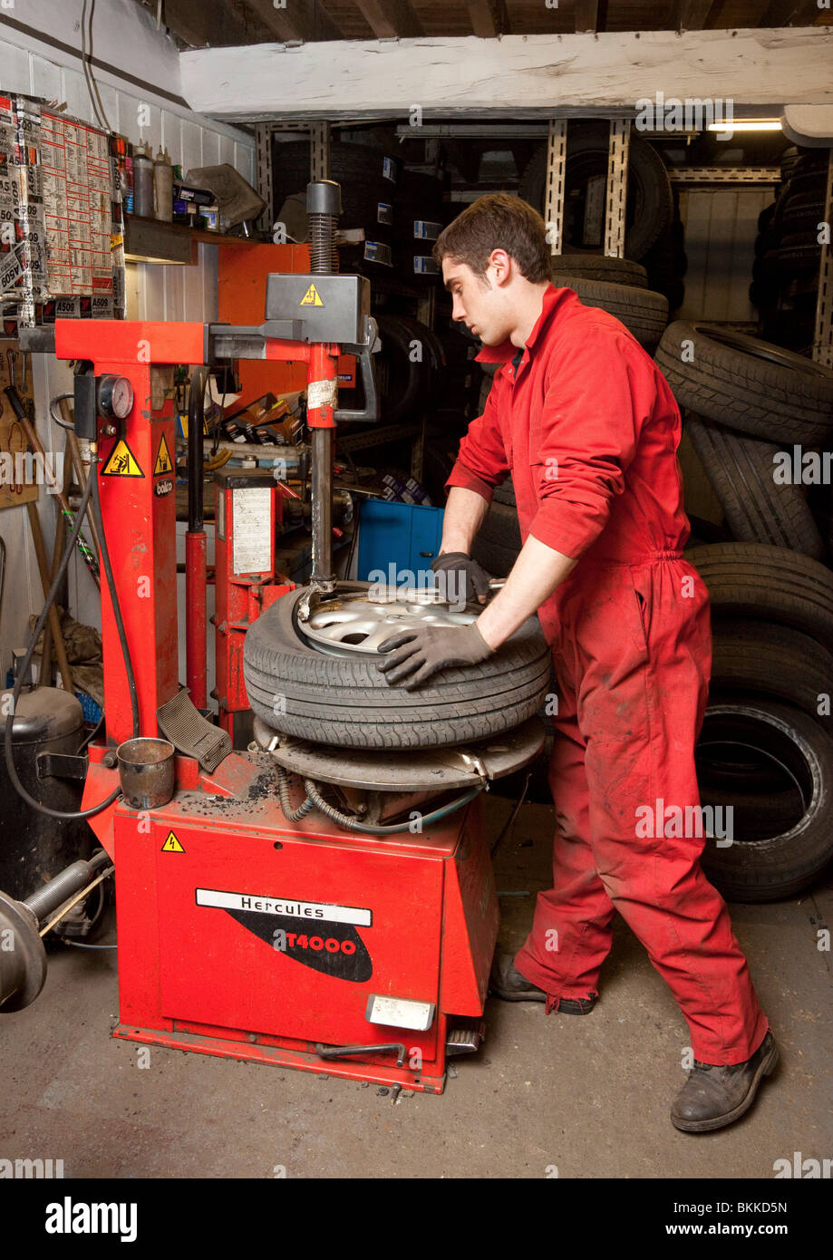 Un garage lavoratore cambiando un pneumatico su una macchina da cerchione ruota Foto Stock