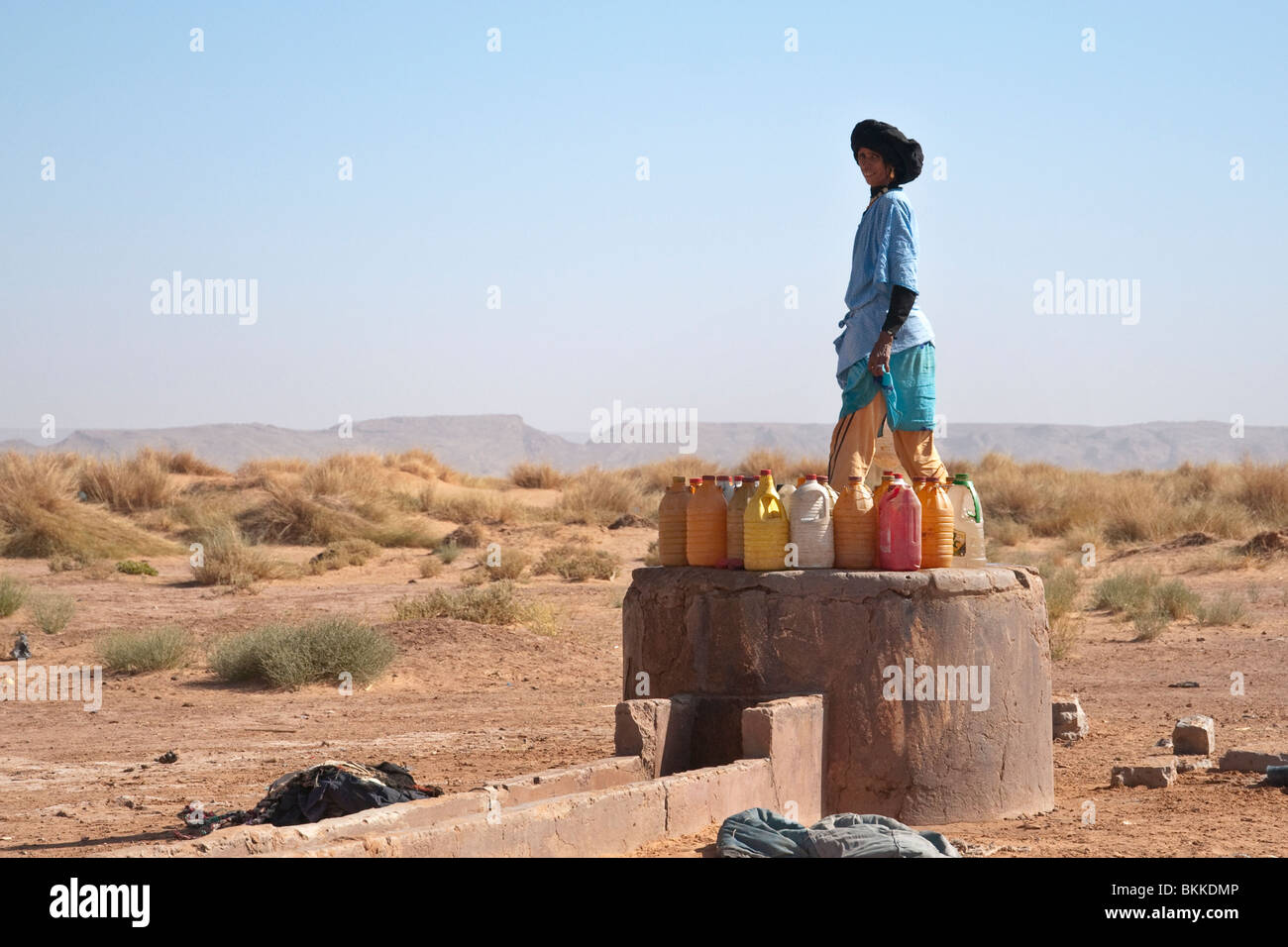 Nomadi donna berbera il riempimento di bottiglie di acqua nel deserto del Sahara, Marocco Foto Stock