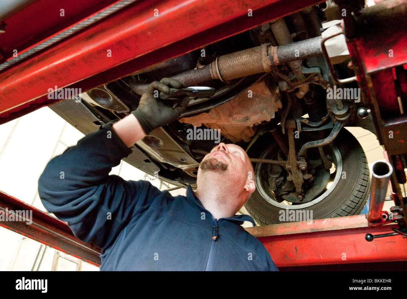 Autofficina controllando la parte inferiore di un auto durante un MOT test nel Regno Unito Foto Stock