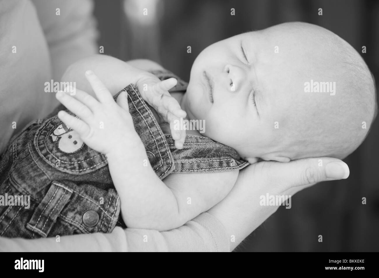 Un bambino dorme tenuto da sua madre Foto Stock