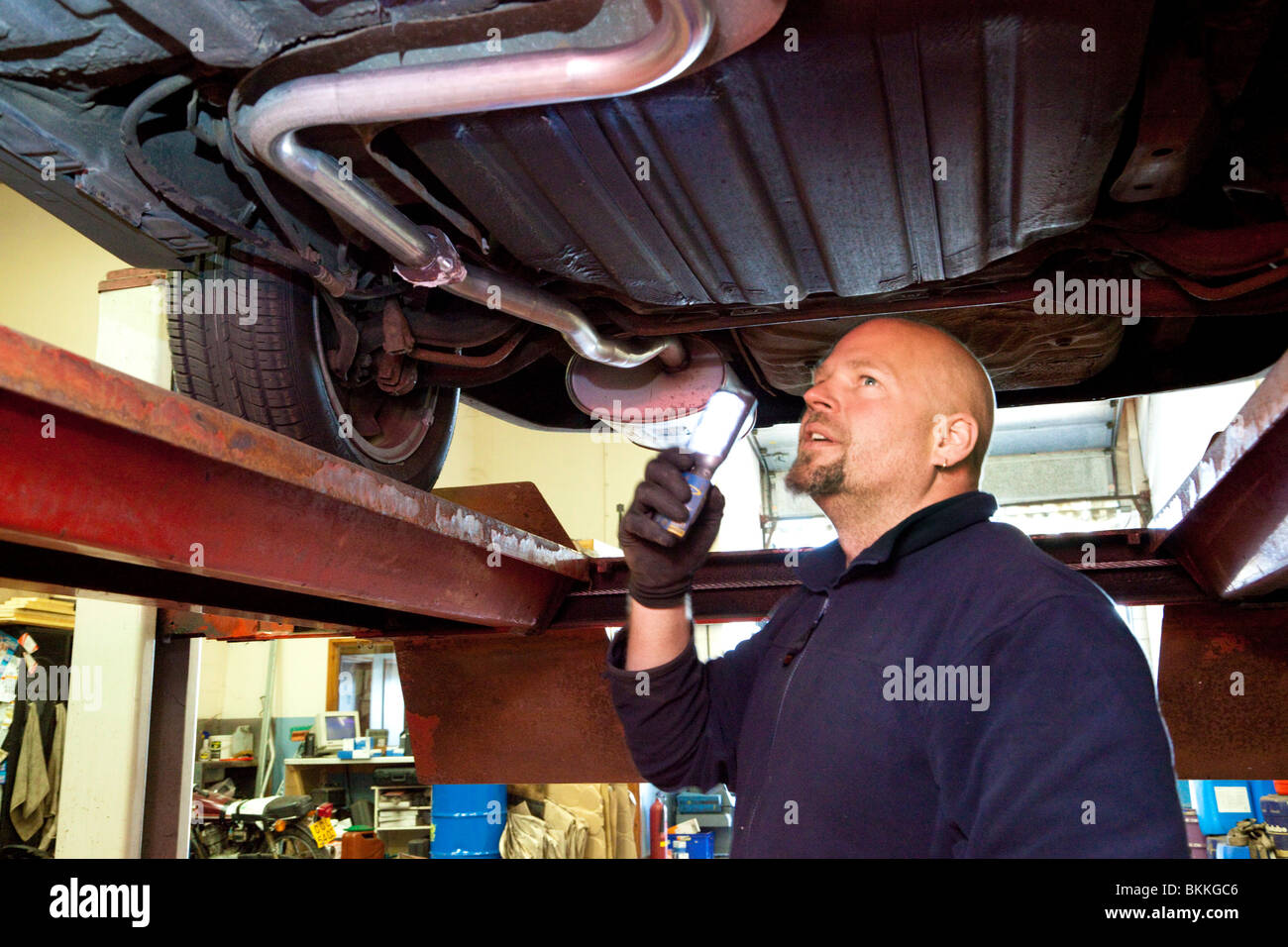 Autofficina controllando la parte inferiore di un auto durante un MOT test nel Regno Unito Foto Stock