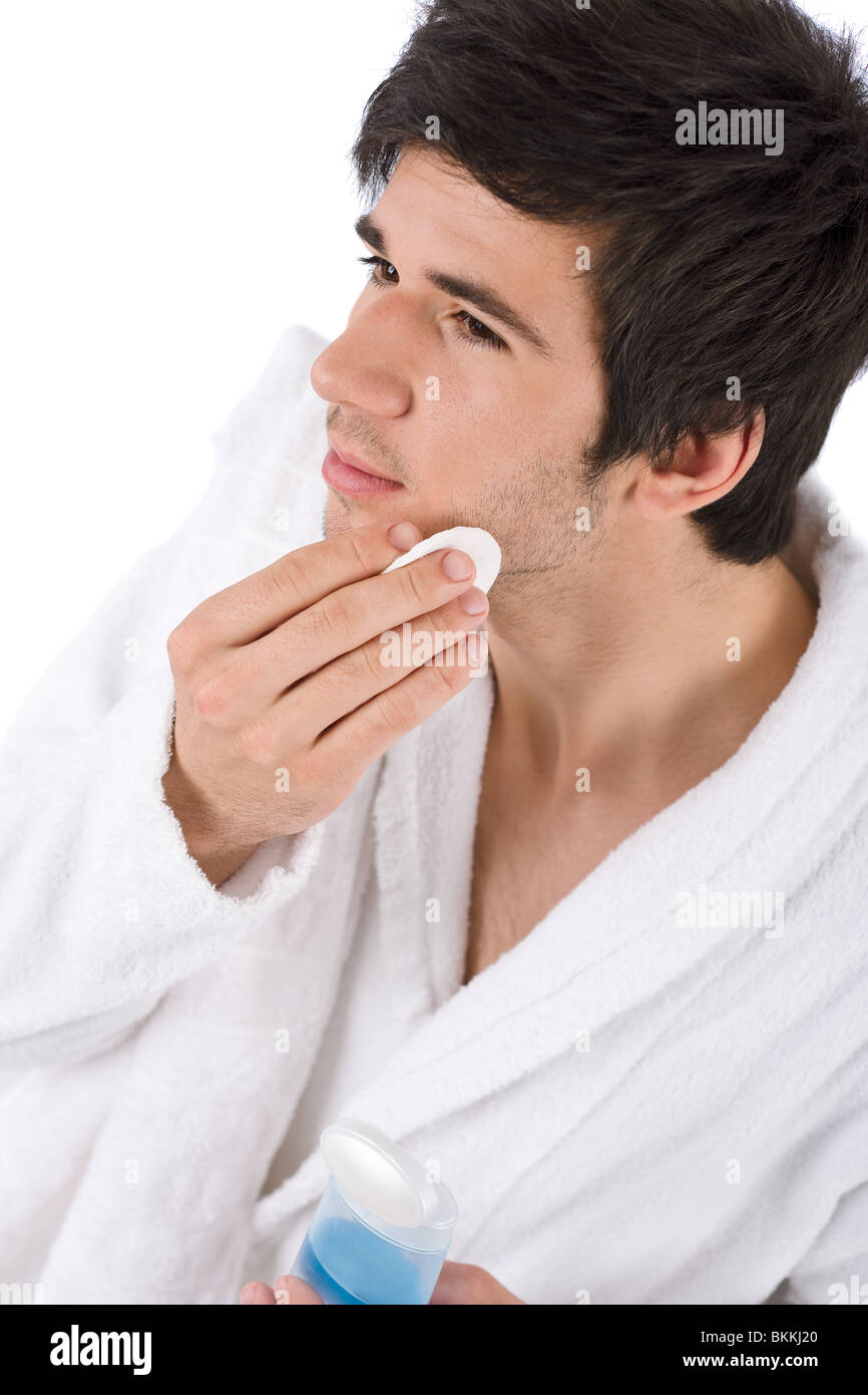 Trattamenti per il viso - Giovane uomo pulizia viso con la lozione su sfondo bianco Foto Stock