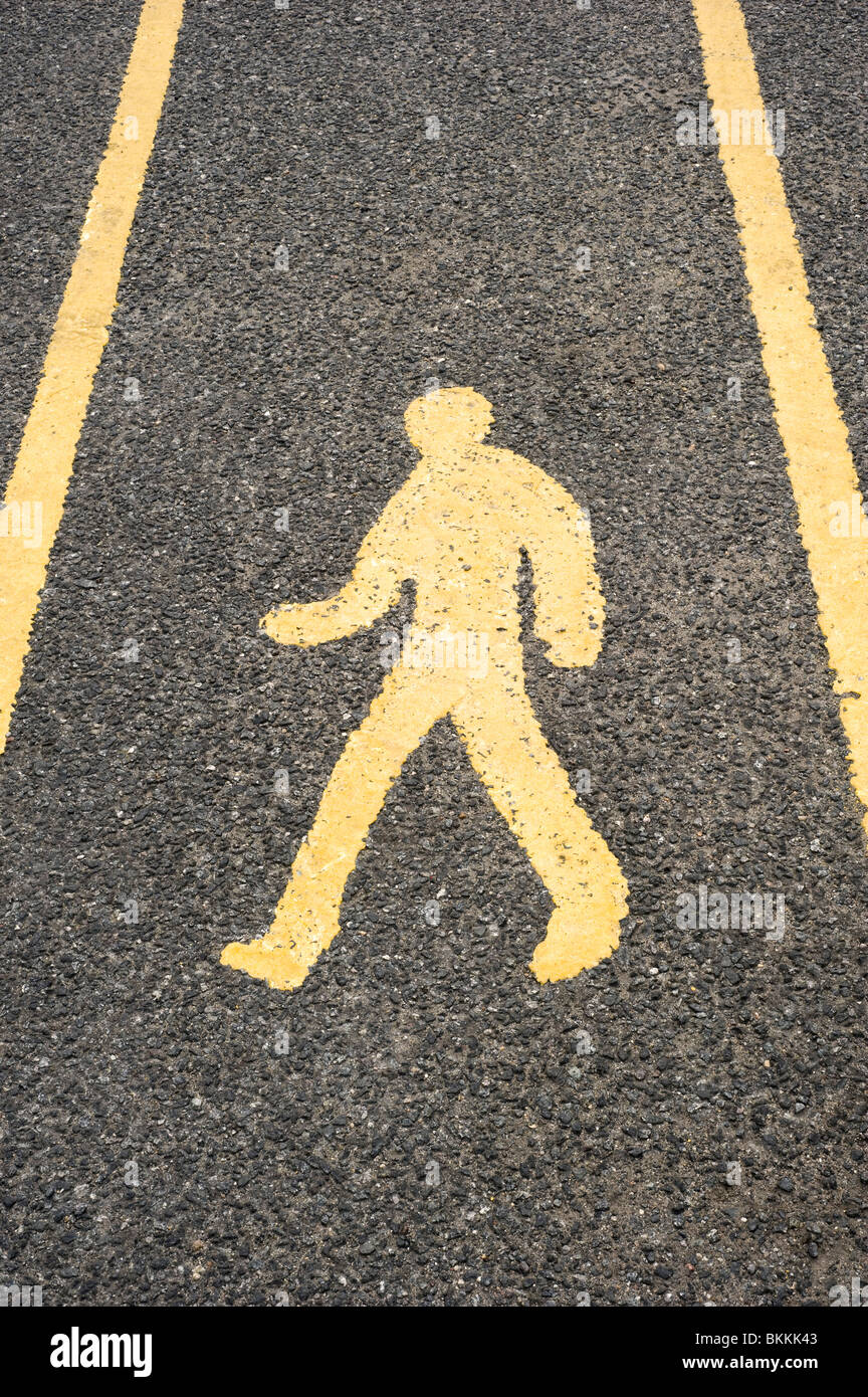 Il giallo Pedonale segno dipinta su una strada asfaltata della superficie in un parcheggio Foto Stock