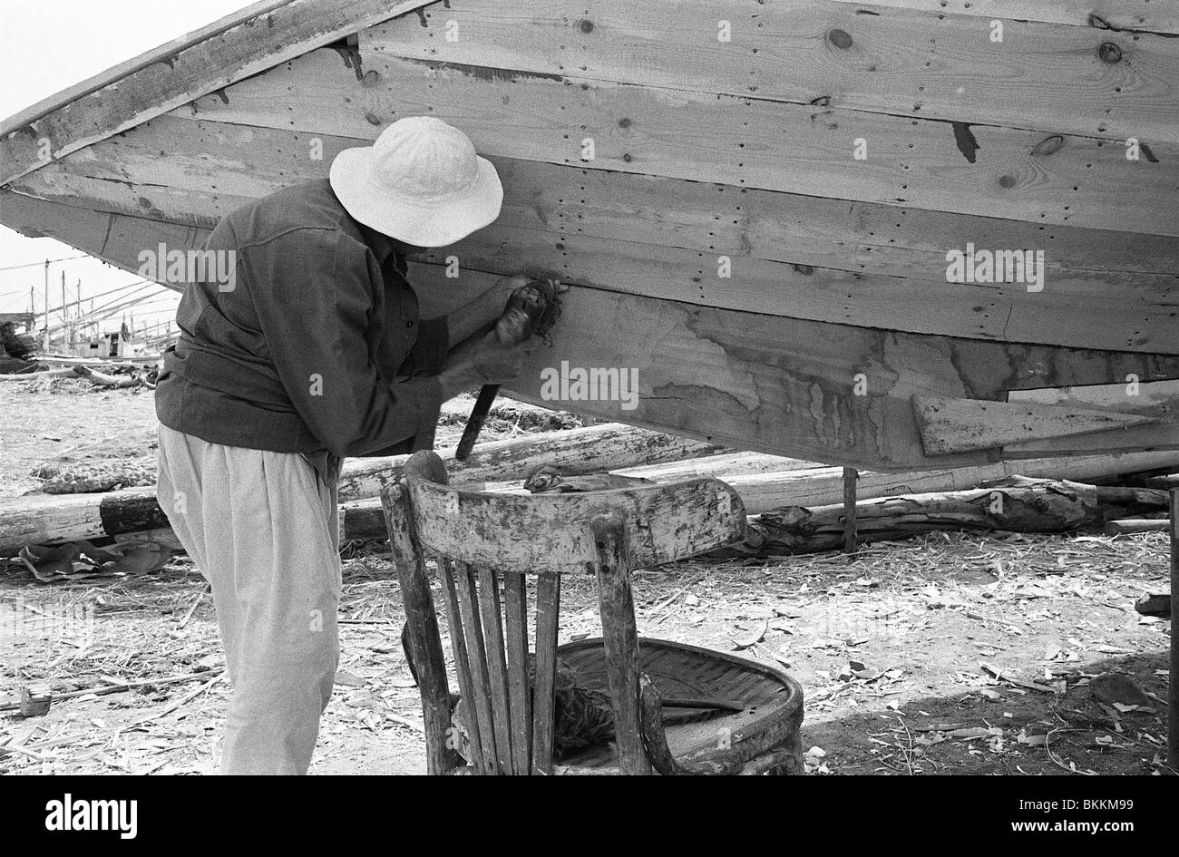 Un uomo l'applicazione di sigillante ad una barca nuova build in El-Matariyyah sul Lago Manzala nel Delta del Nilo di Egitto Foto Stock
