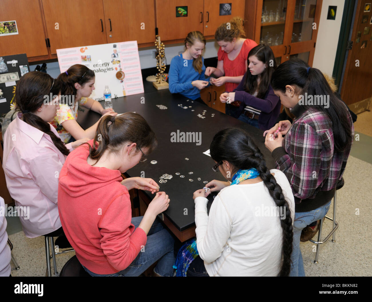 Alta scuola ambientale riunione del club. Gli studenti utilizzano il carbonato di sodio può flip top per la realizzazione di bracciali di vendere come una raccolta di fondi. Foto Stock