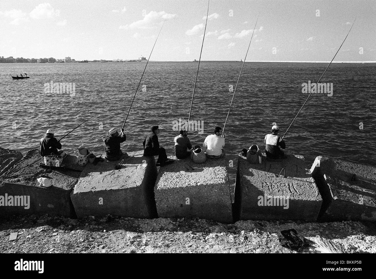Un gruppo di uomini godono di una macchia di pesca sulla parete del porto orientale di Alessandria, Egitto Foto Stock