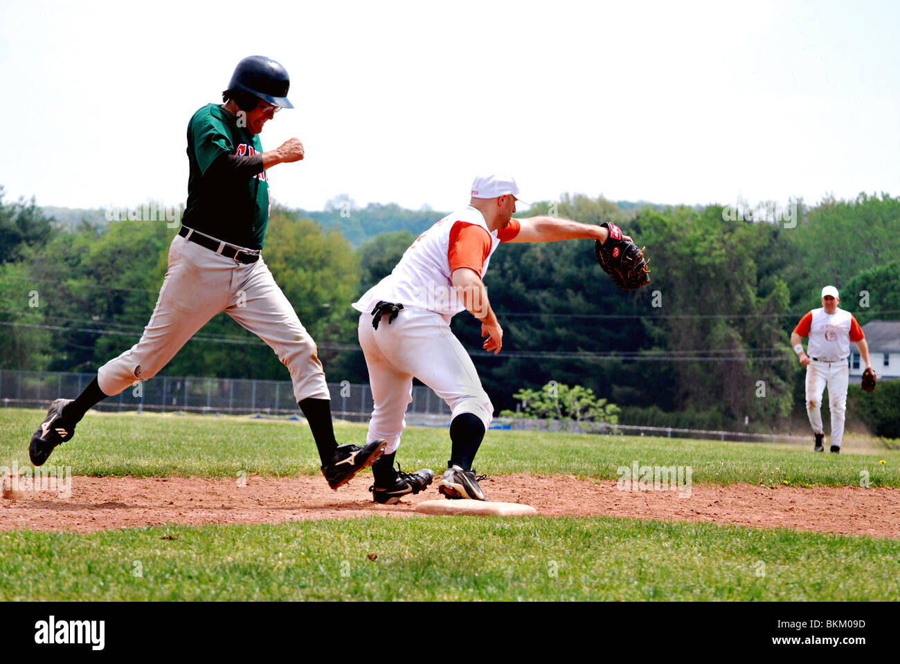 Mens baseball league. primo baseman tenta di ottenere il runner fuori sulla prima base. Foto Stock