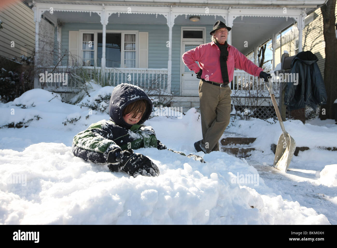 Padre e figlio di godere di una piacevole mattinata di riproduzione e spalare la neve in Charlottesville, Virginia. Foto Stock