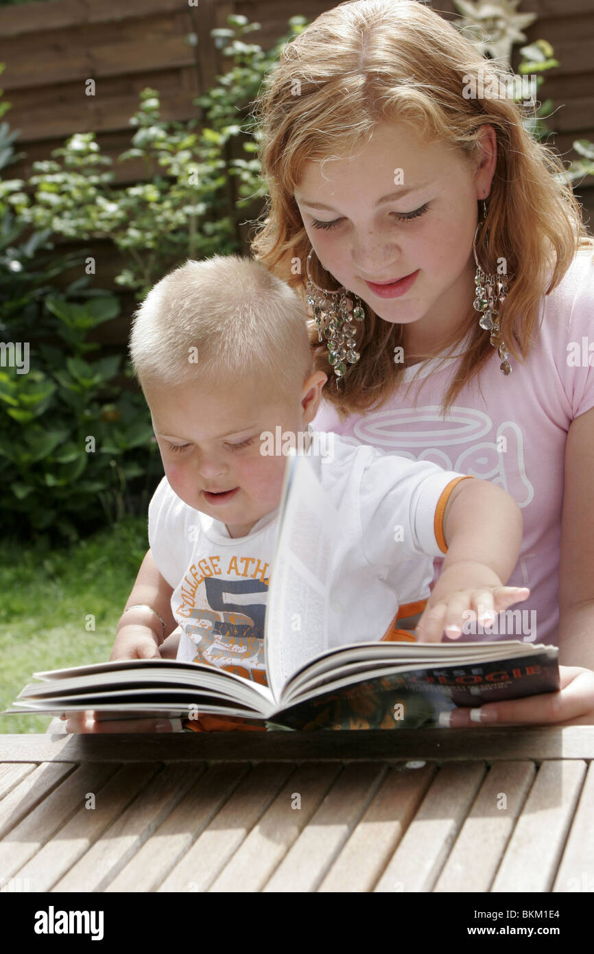 La sindrome di Down: ragazza adolescente la lettura di un libro di un  bambino con una malattia genetica, sindrome di Down, potrebbero essere  fratelli o babysitter teen o teenage mamma Foto stock -