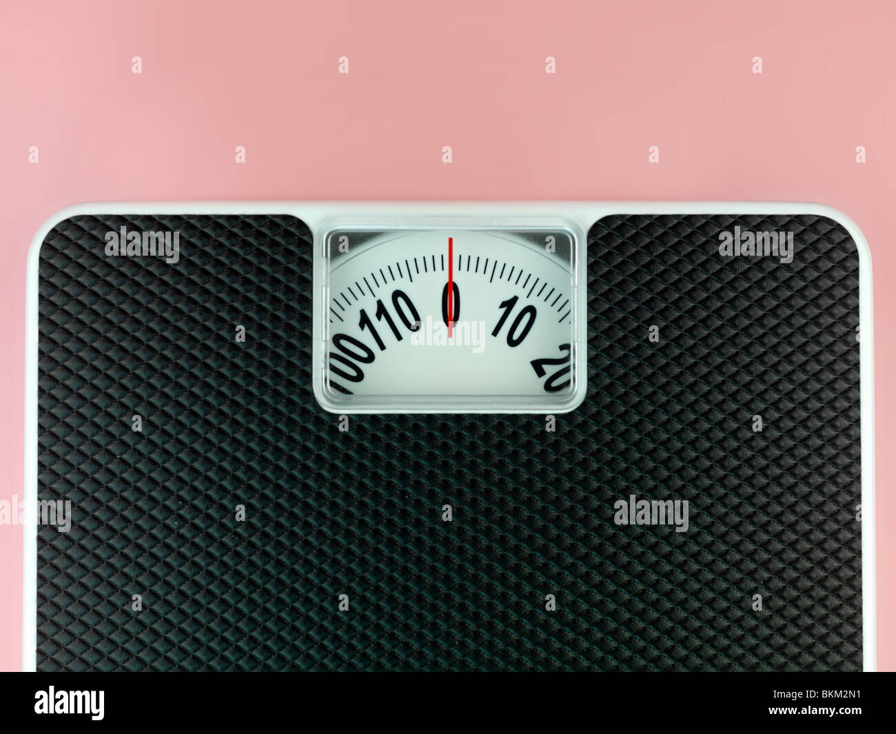 Una serie di bilance pesapersone isolata contro un sfondo rosa Foto Stock