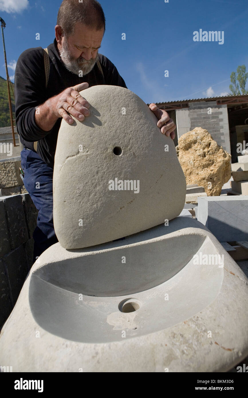Pierre, uno scalpellatore, dimostra lavelli che egli mestieri da singole pietre alla cava di Entrevaux, sulle Alpi francesi Foto Stock