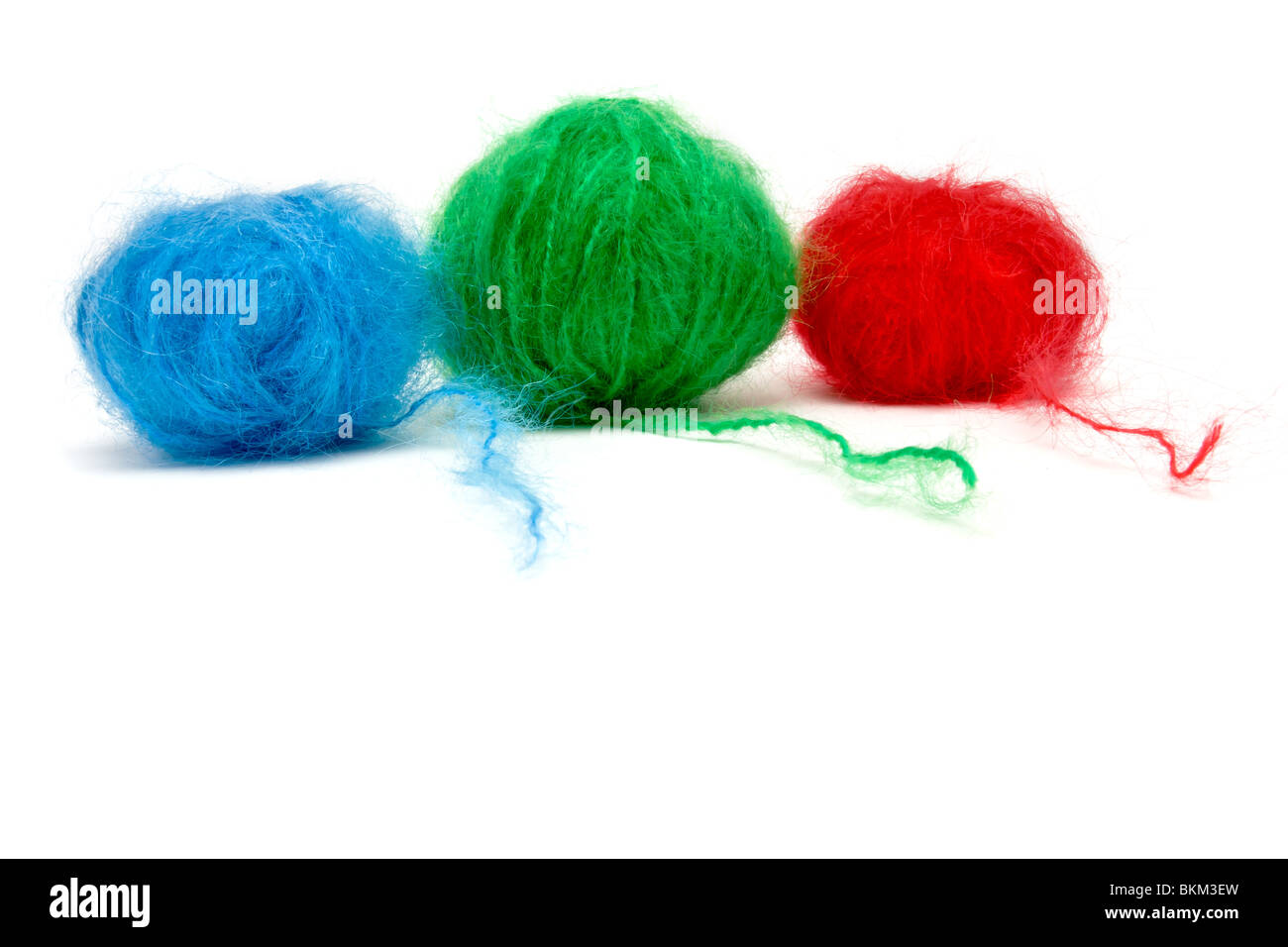 Una linea di colore rosso, verde e blu di palline di lana mohair isolata contro uno sfondo bianco. Foto Stock