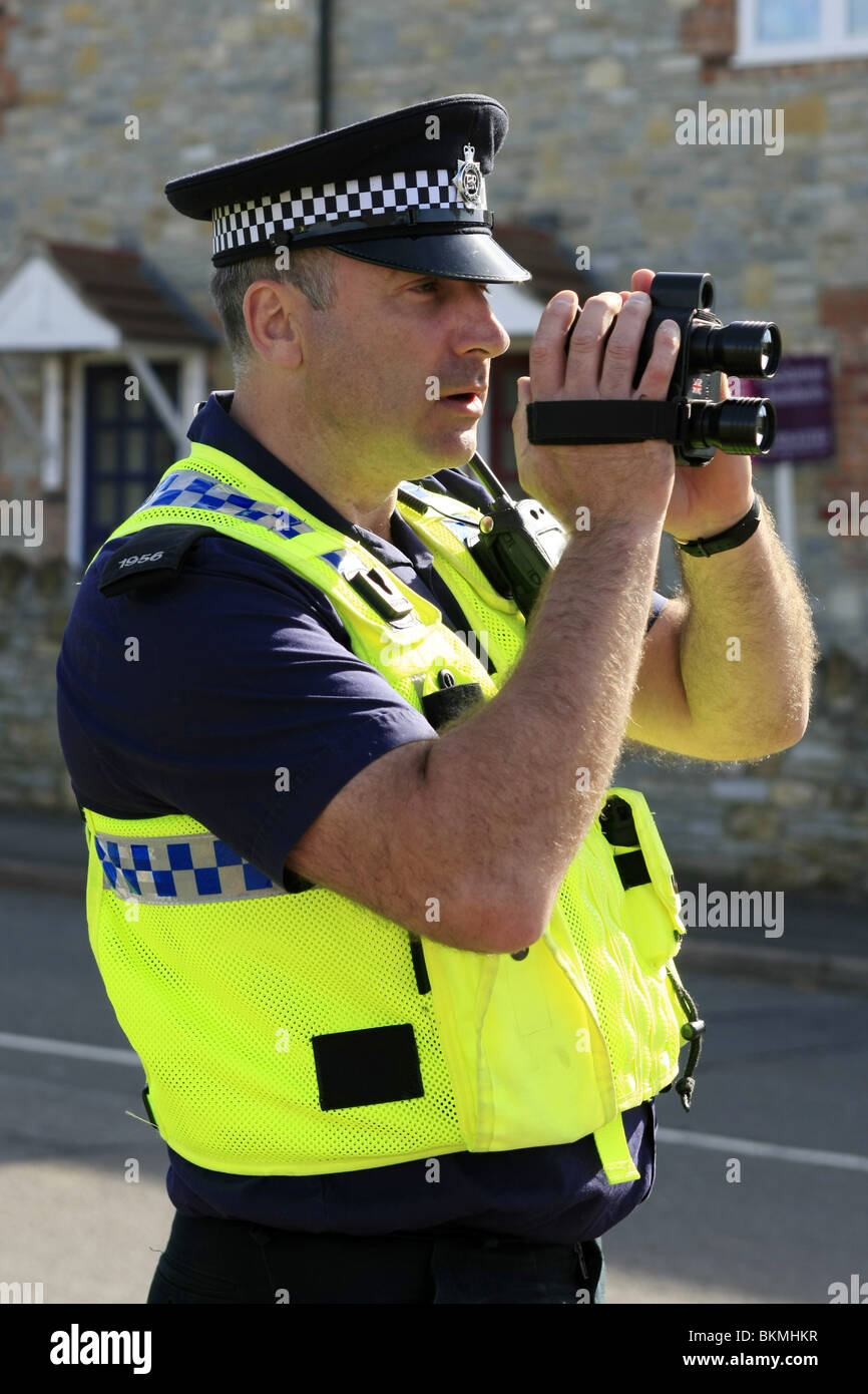 British funzionario di polizia con un hand-held speed camera in un 30mph zona Foto Stock